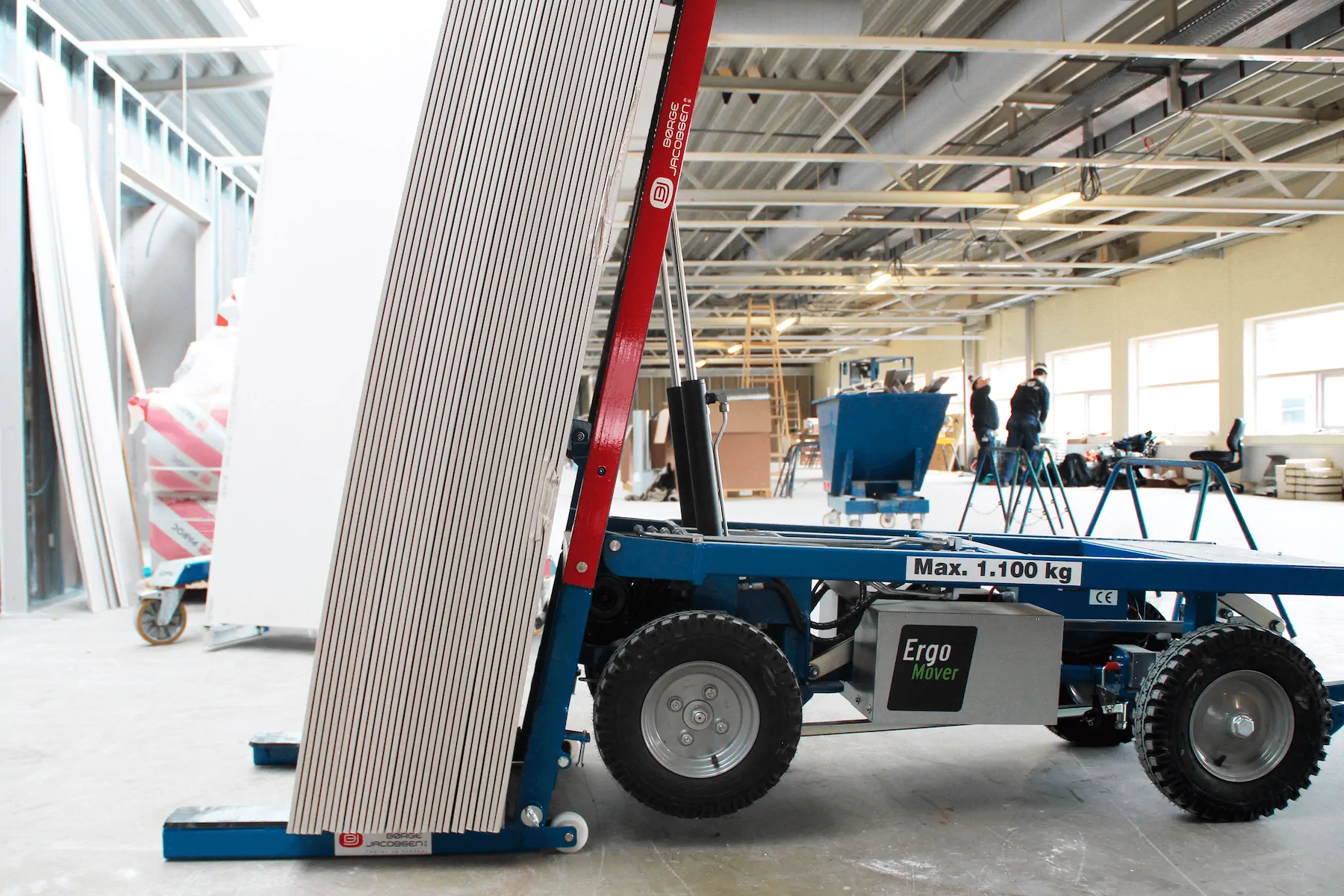 ErgoMover Manipulator holding a tall stack of plasterboard sheets upright inside a building under construction.
