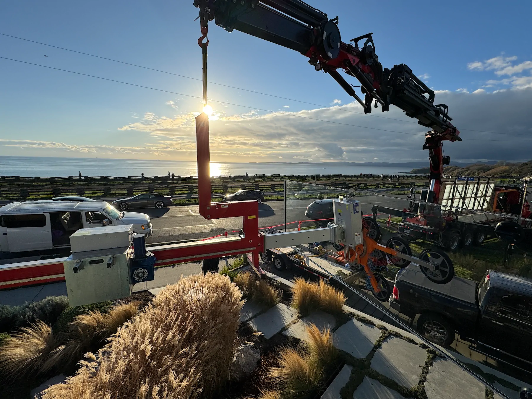 Truck-mounted crane lifting the red counterbalance beam off a trailer at the roadside.