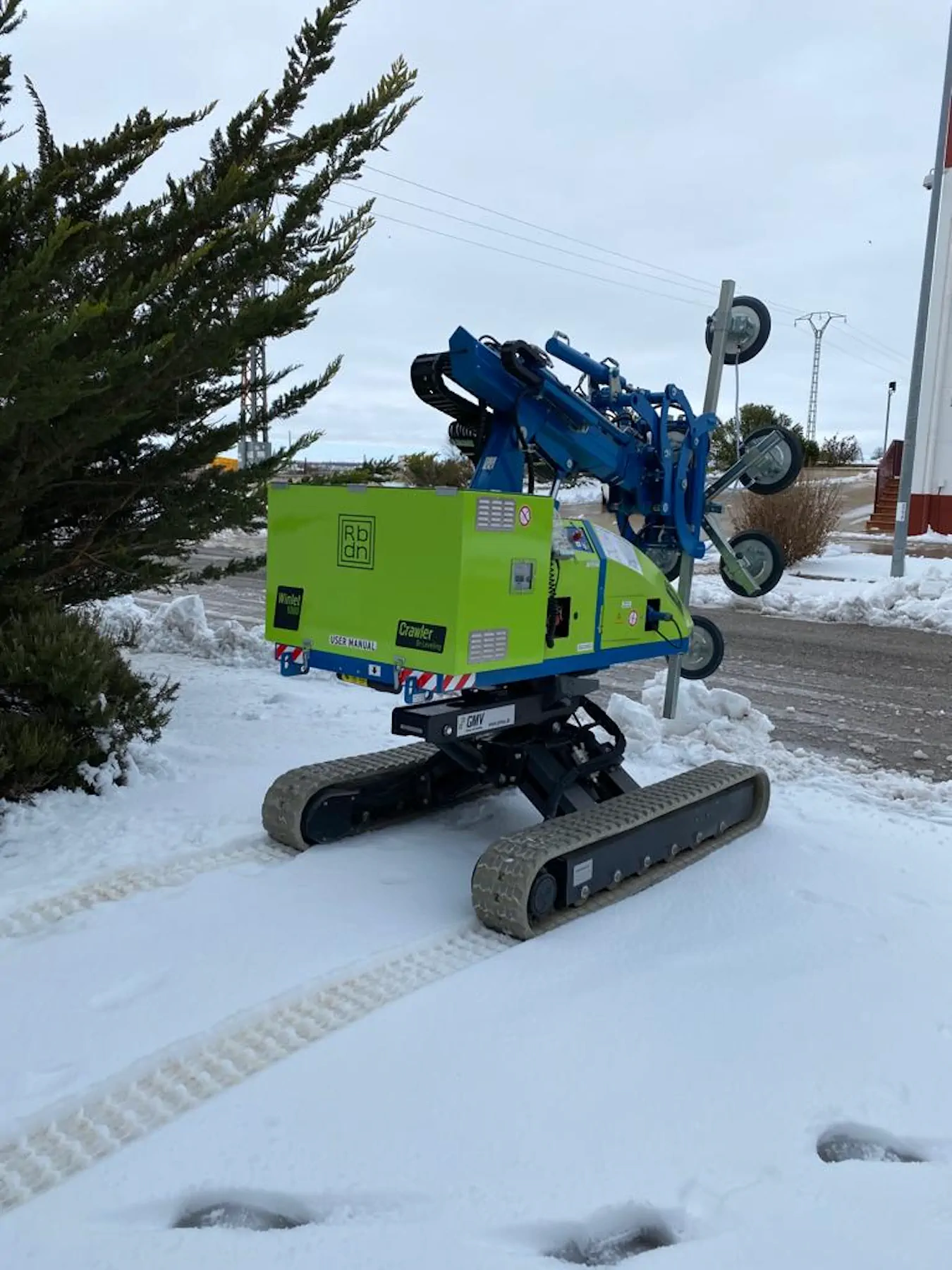 Winlet 1000 Crawler ER on snow-covered ground beside a road, with its arm folded up and suction cups raised.