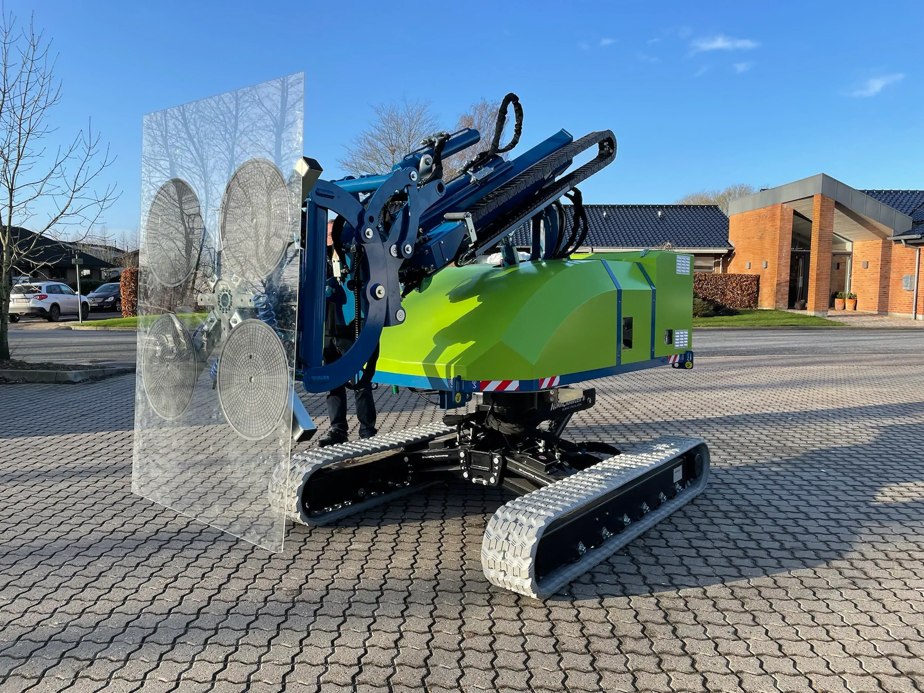 Winlet 1000 Crawler ER carrying a large clear glass pane on its four suction cups across a paved courtyard.