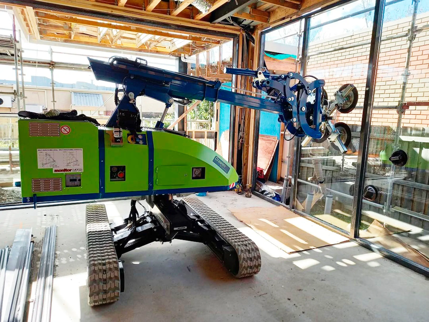 Winlet 1000 Crawler ER inside a building under construction with its arm extended toward a glazed wall opening.